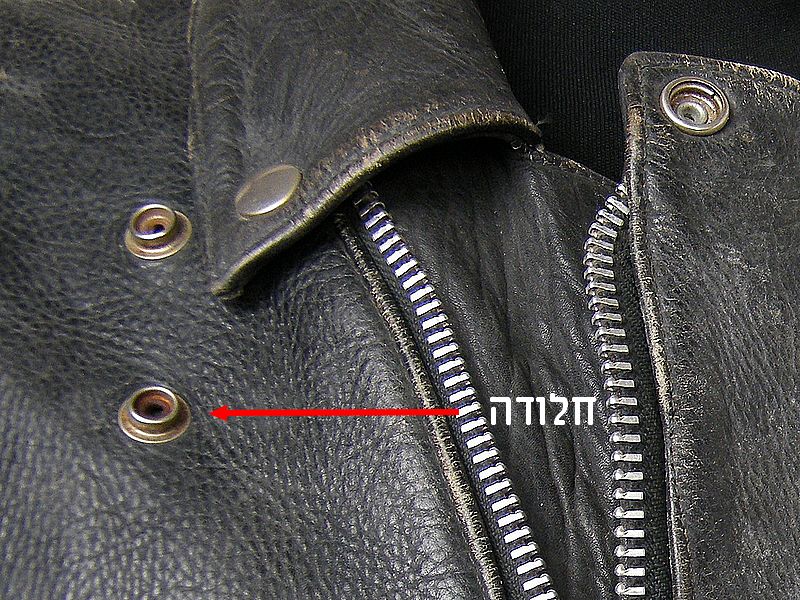 תקריב של חלודה על כפתור ורוכסן במעיל עור Harley-Davidson וינטג’ משנות ה־80 לפני השחזור.