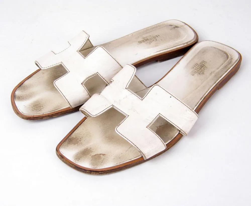 סנדלי Hermès Oran לבנים כפי שהגיעו לסטודיו עם כתמים ושחיקת צבע